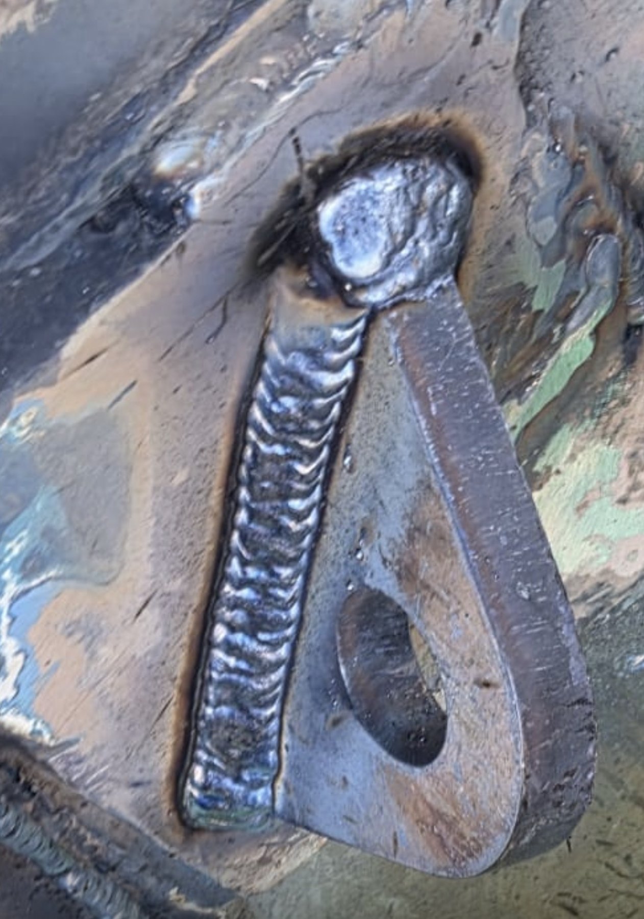 Close-up of a fillet weld on a new fender pad eye welded to the hull doubler plate, showing a clean uniform weld bead